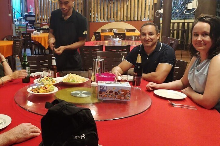 Un gruppo di persone cena in un ristorante con tavoli rossi e diversi piatti sul tavolo. 4