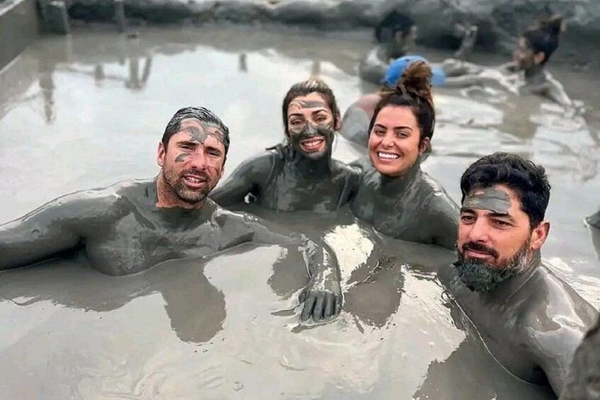 Personas en un cuerpo de agua fangosa, posiblemente un baño de barro o manantial termal natural. 1