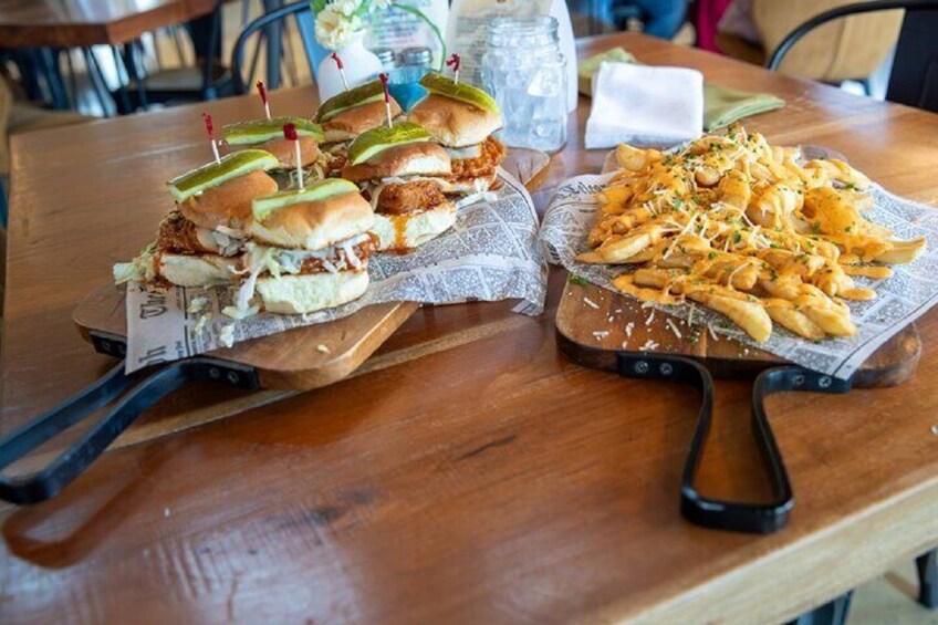A wooden table with two trays of food: one with burgers and the other with fries. 3