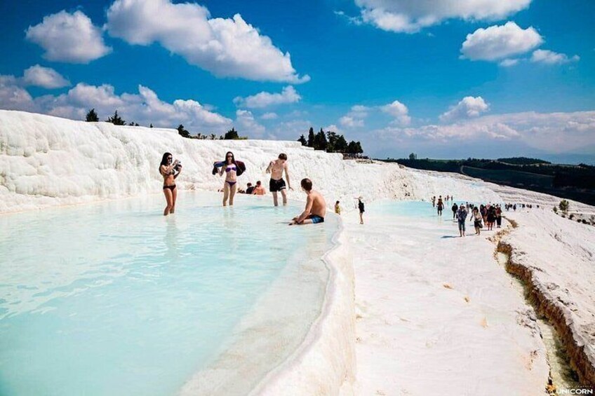 A natural hot spring with people bathing and walking around. 3