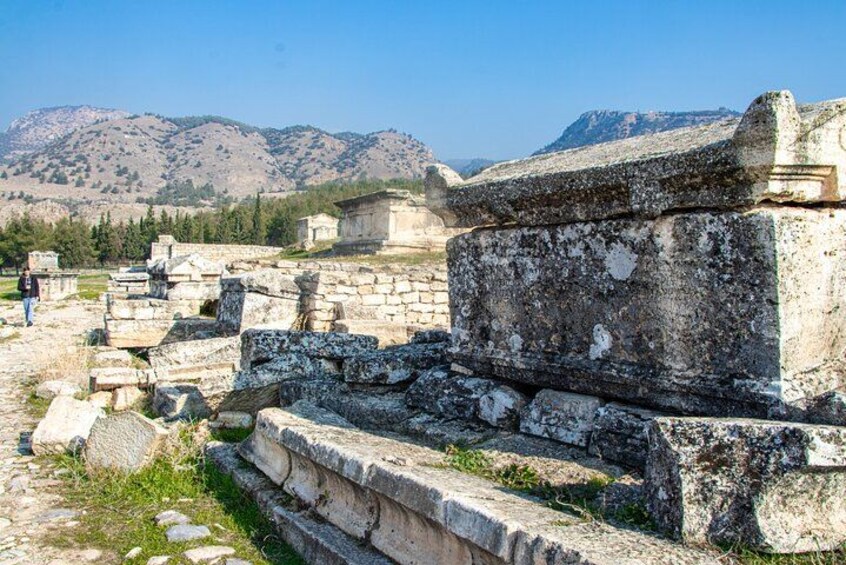 Ancient ruins with stone steps and walls, set against a mountainous backdrop. 2