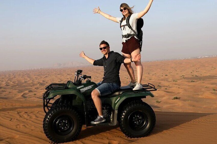 A person riding a green ATV in a desert with sand dunes. 5