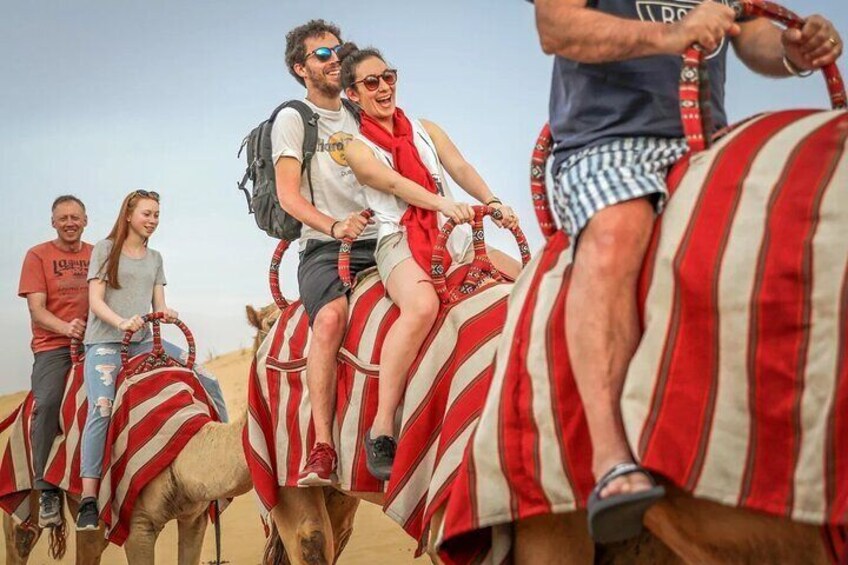 People riding camels in a desert. 4