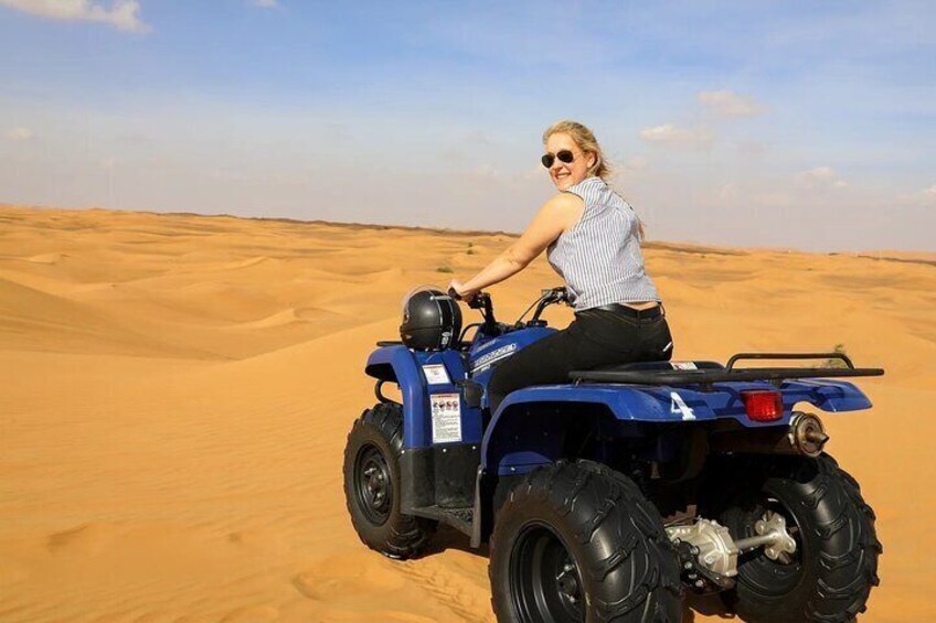 A person riding a blue quad bike in a desert. 2