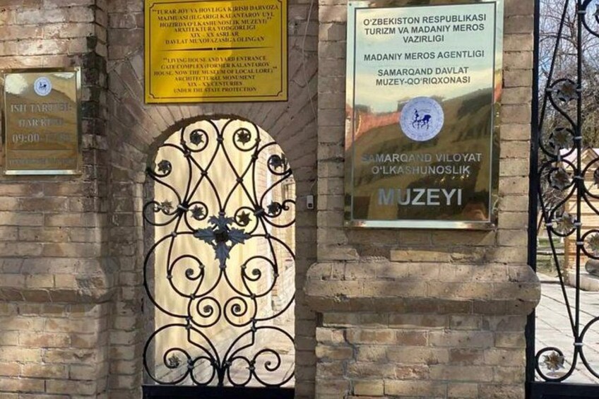 A metal gate with intricate designs, a plaque with text, and another plaque with a logo and text. 2