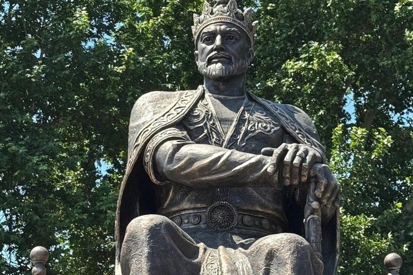 A statue of a historical figure with a crown, seated with hands clasped. 5