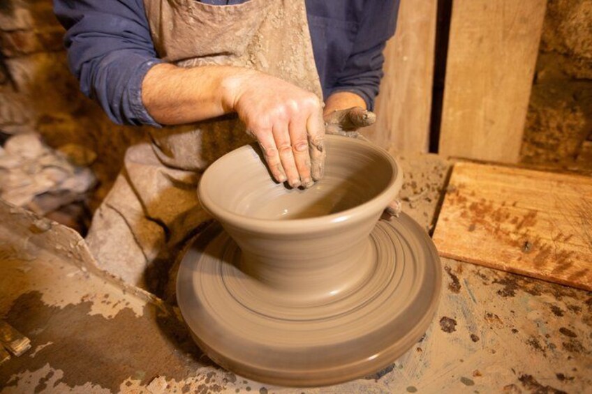 A person shaping a clay pot on a pottery wheel. 3