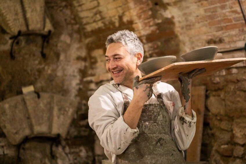 A person carrying a tray with plates, in a stone building with brick walls. 2