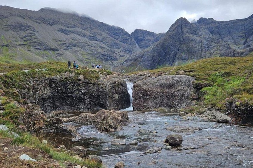 Ett vattenfall, ett bergigt landskap och berg i bakgrunden. 2