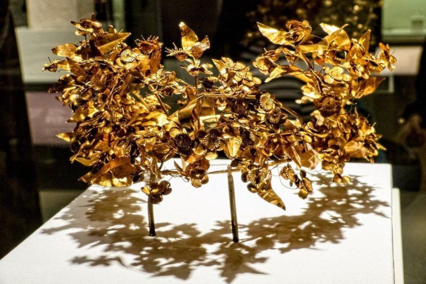 A golden sculpture of a tree with intricate details on a white pedestal. 5