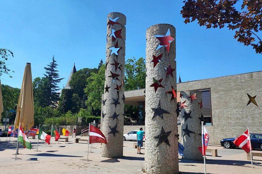 A plaza with stone pillars decorated with stars, flags, and a building in the background. 5