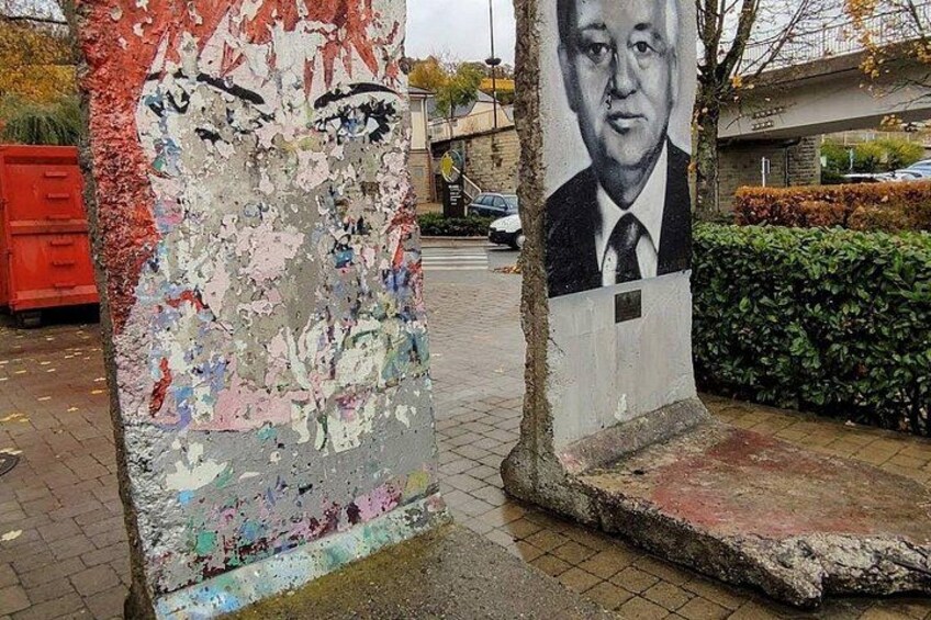 A street with a damaged wall and a portrait of a man. 4