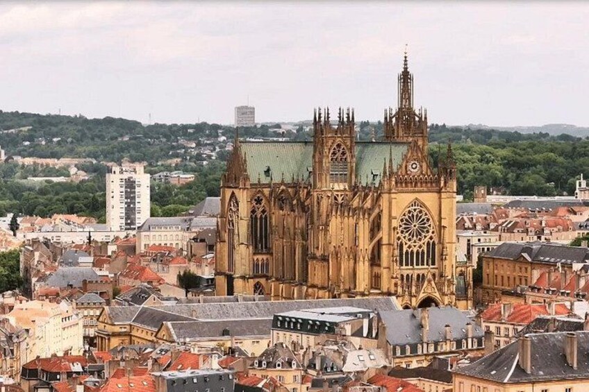 A Gothic cathedral with twin spires and a rose window, surrounded by a densely packed cityscape. 1