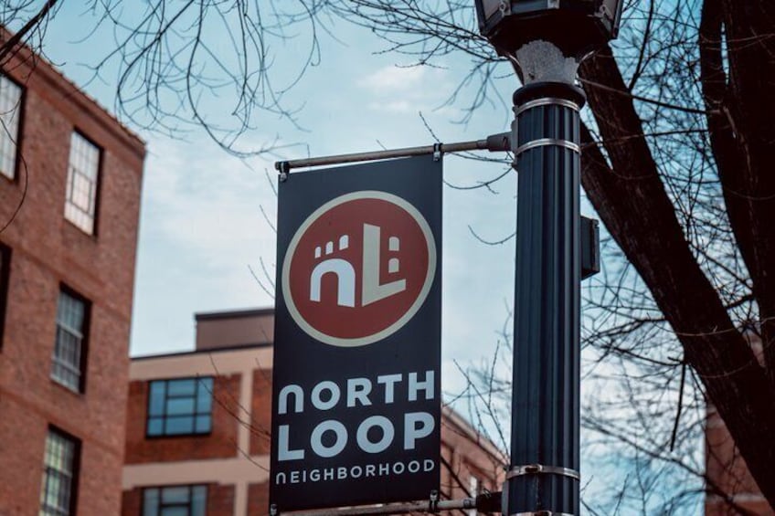 A sign for North Loop neighborhood with a circular logo and text. 1