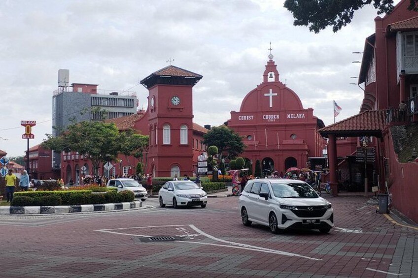 A red church with a clock tower, a white car, and a red building with 'CHRIST CHURCH MELAKA' written on it. 5