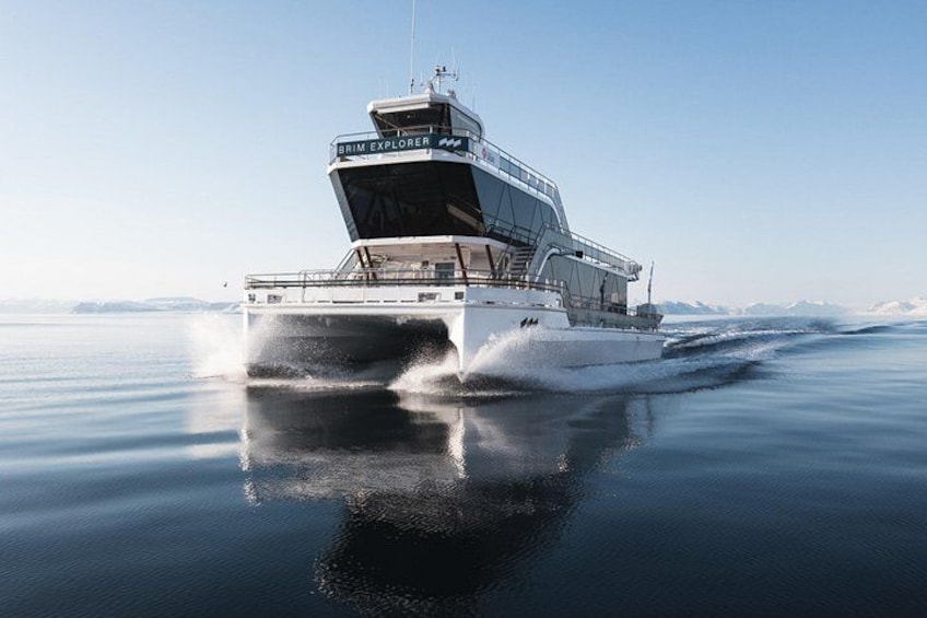 A large, modern yacht named 'BRIM EXPLORER' cruising on calm waters with a clear sky and distant mountains in the background. 1