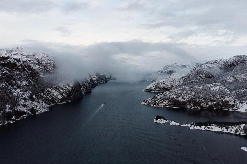 A snow-covered fjord with a boat on the water. 3