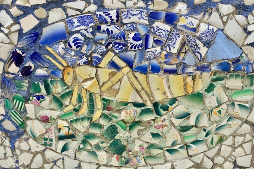 A mosaic with blue and white tiles depicting a fish and green tiles with floral patterns. 3