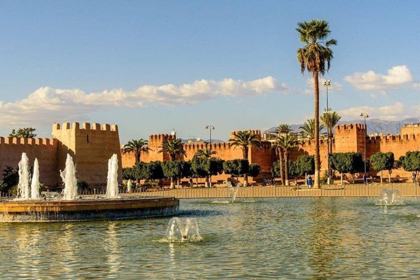 Una fortaleza histórica con un foso, palmeras y una fuente. 1