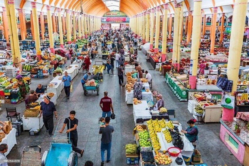 A bustling indoor market with rows of stalls selling fruits, vegetables, and other goods. 1