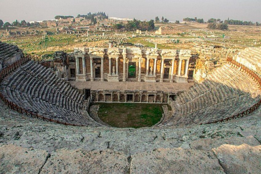 An ancient amphitheater with stone seating and a central stage. 4