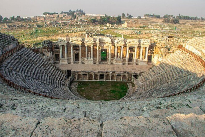 An ancient amphitheater with stone seating and a central stage. 2