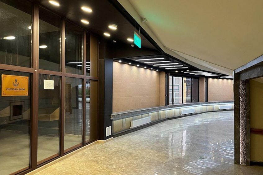 A corridor with glass doors, a sign, and a tiled floor. 4