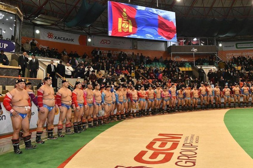 A sumo wrestling event with participants lined up on a mat. 1