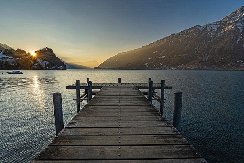 Un molo di legno si protende in un lago tranquillo, con montagne sullo sfondo. 4