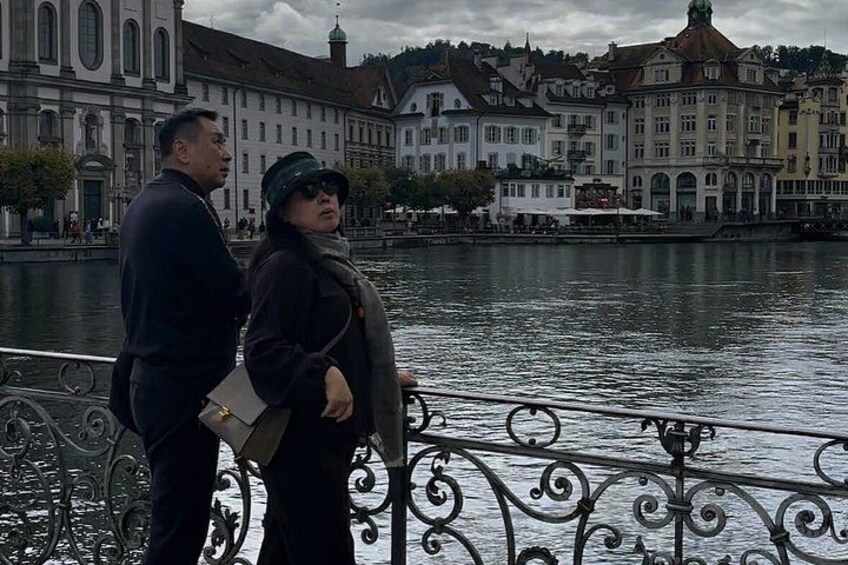 A couple standing by a river with a cityscape in the background. 4