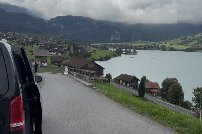 A road curving through a village with houses and a lake in the background. 3