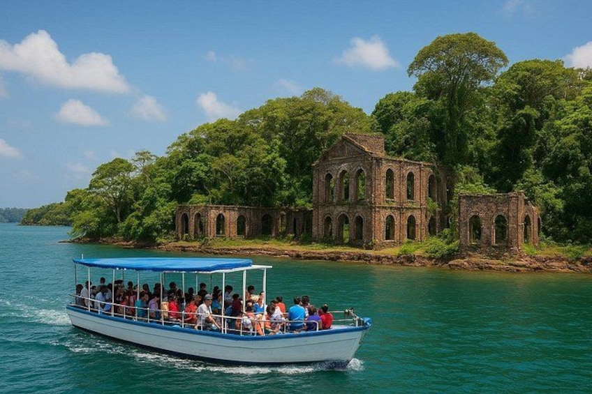 A boat with passengers, a large brick building, and a forested island. 1