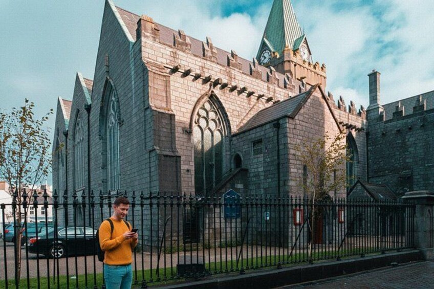 A historic church with a clock tower, a black fence, and a person standing in front. 5