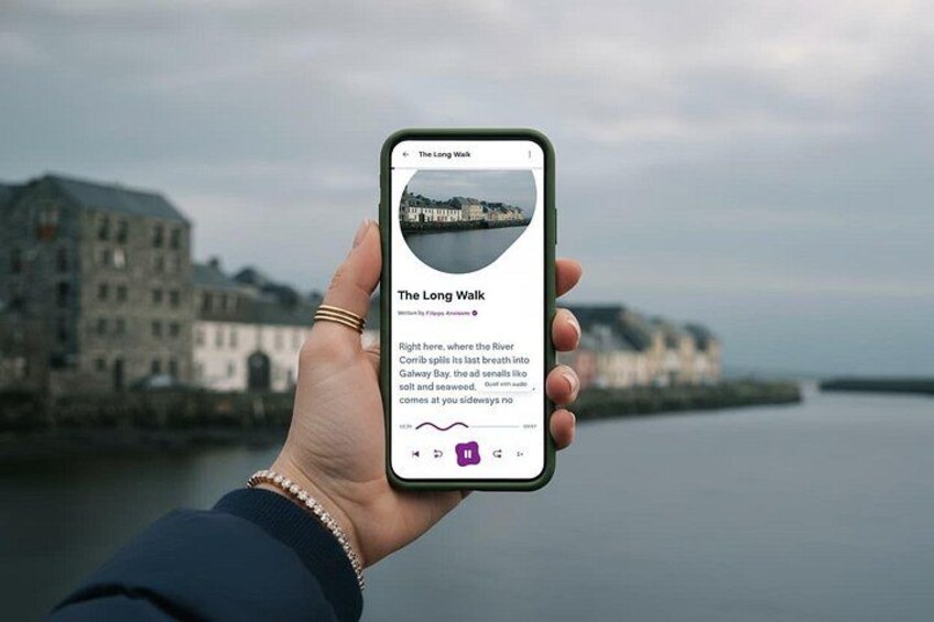 A hand holding a smartphone displaying a scenic view of The Long Walk with a river and buildings in the background. 1