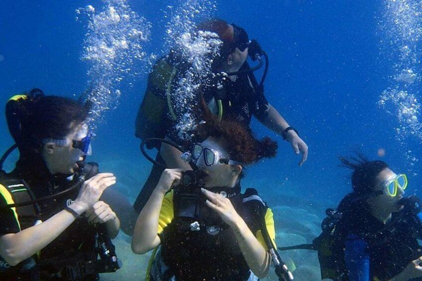 Three scuba divers underwater with bubbles around them. 2