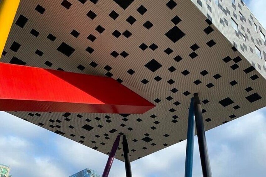 A modern building with a geometric facade and a red structure in the foreground. 2