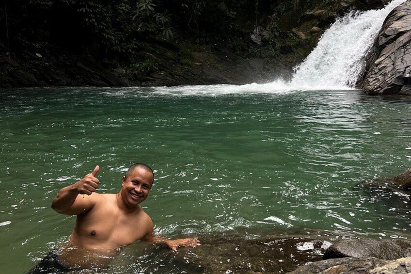 A person in a natural water body with a waterfall in the background. 3