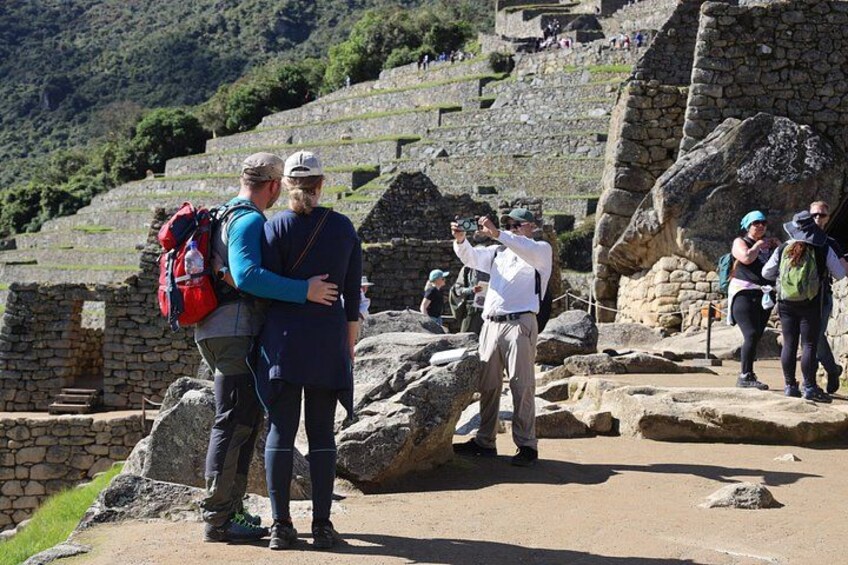 Toeristen bij een oude archeologische plek met stenen ruïnes en een bergachtig achtergrond. 2