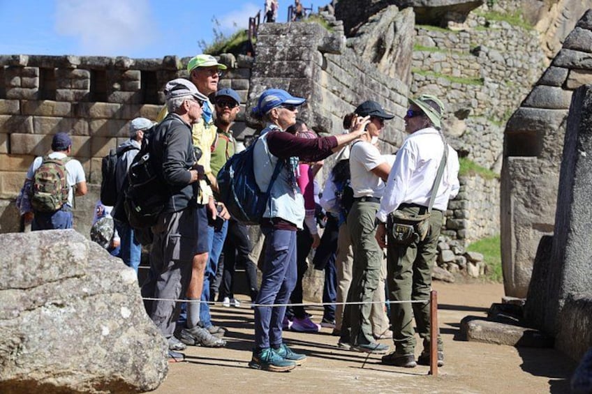Des touristes visitent un site archéologique avec des ruines en pierre, et un guide accompagne un groupe. 3