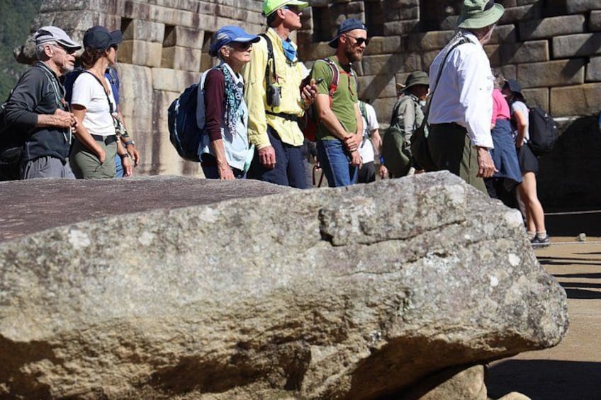 Un groupe de personnes se tient près d’une grande formation rocheuse, peut-être sur un site historique. 4