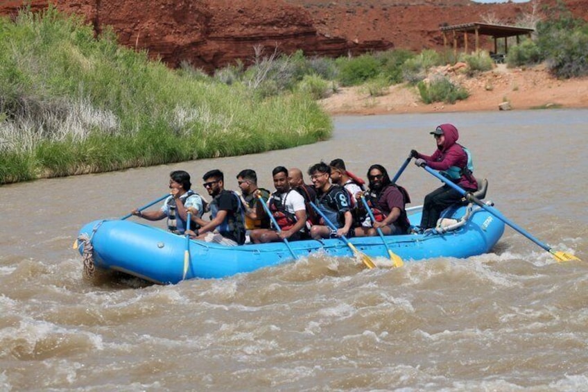 A group of people in a blue raft navigating a river. 2