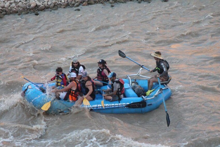 A group of people in a blue inflatable raft navigating through a river. 3