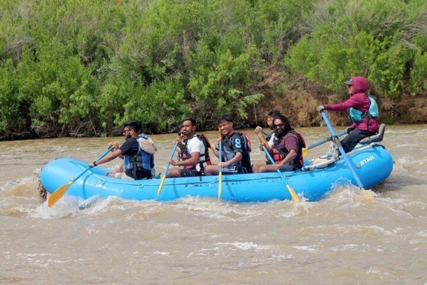 A group of people in a blue inflatable raft on a river. 3