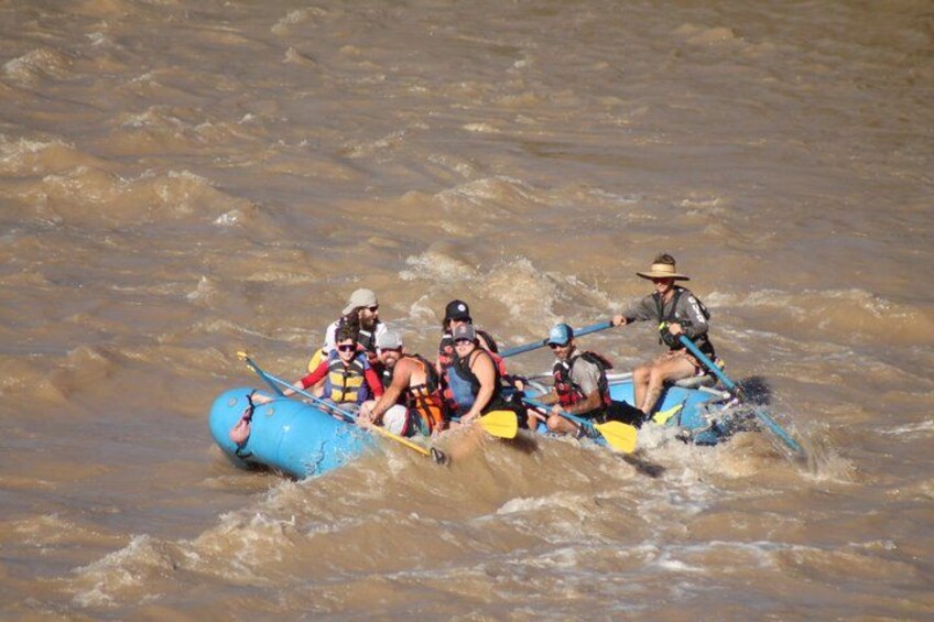 A group of people in a blue raft navigating through murky water. 4