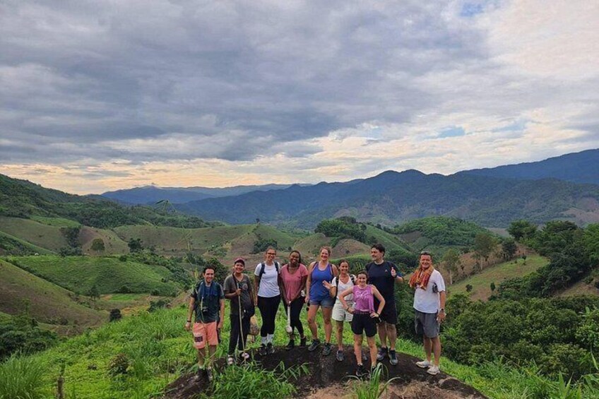 A group of people standing on a hill with a mountainous landscape in the background. 1