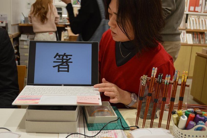 Una persona che utilizza un portatile con schermo che mostra caratteri cinesi, circondata da materiale da cancelleria come matite e penne. 5