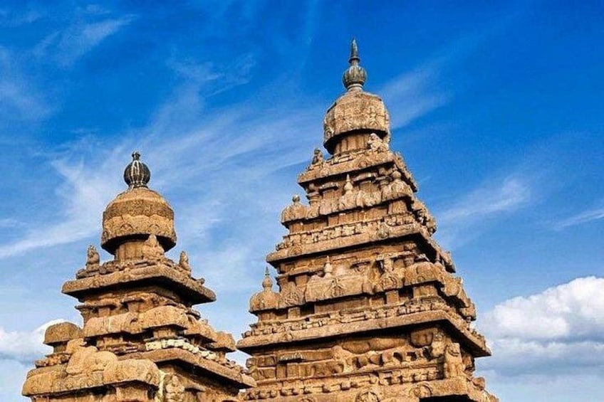 Two ancient stone structures with multiple tiers and intricate carvings against a clear blue sky. 4