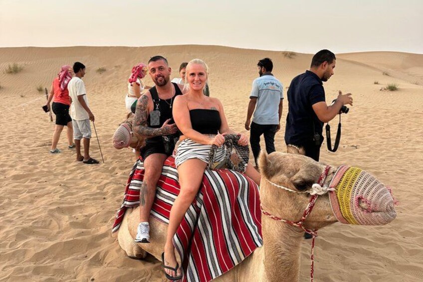 A camel with a rider and a guide in a desert. 2