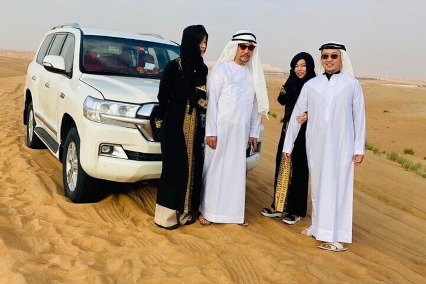 A group of people standing in a desert with a white SUV. 5