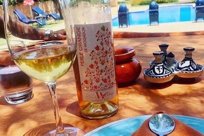 A bottle of Perle d'Orange wine, a glass of white wine, and Moroccan salt shakers on a table. 3